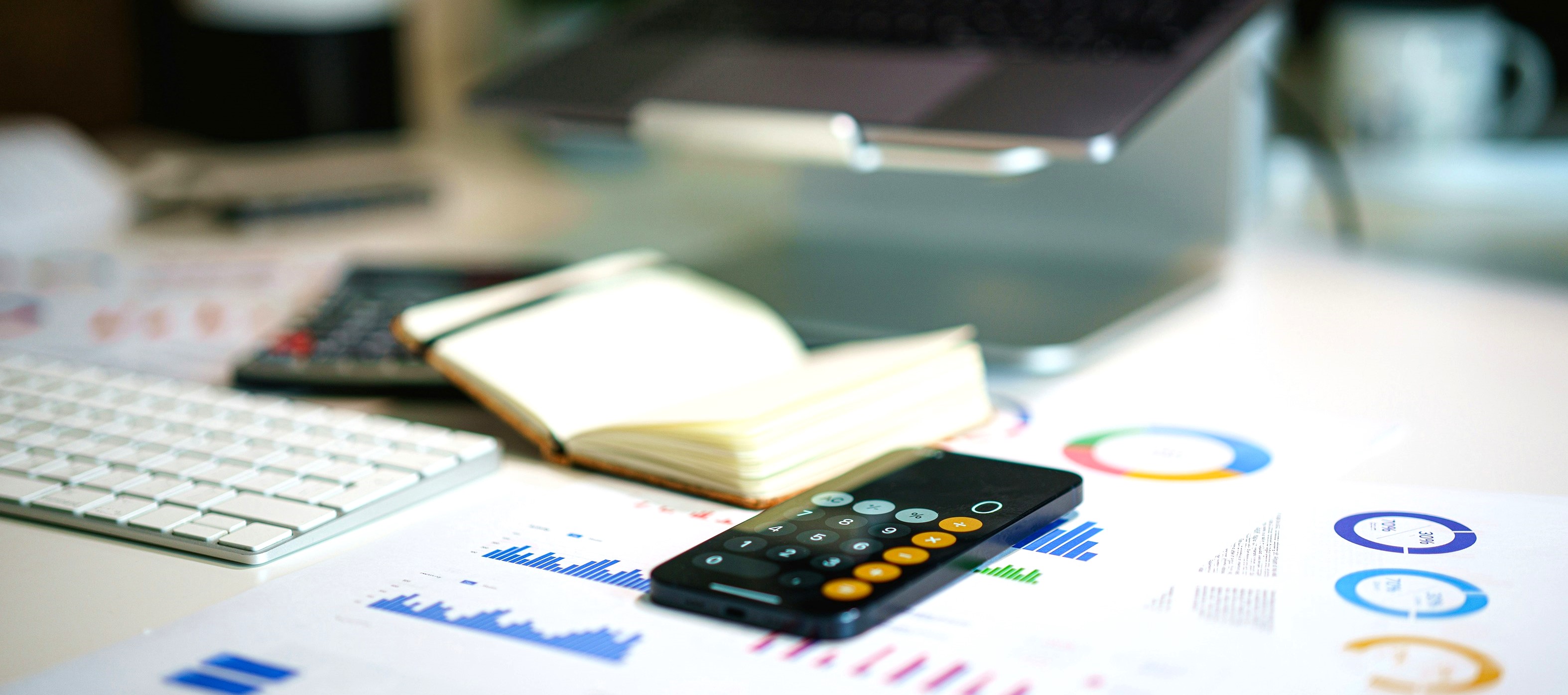 A desk with a calculator, notepad, and a laptop