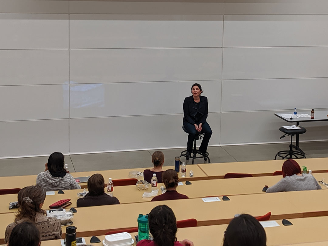 Eliza VanCort, seated in lecture hall 4 and speaking to an audience