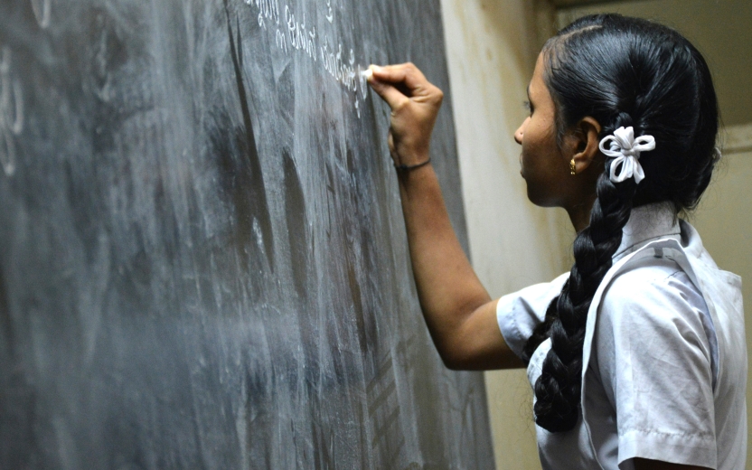 A school girl writing on a black board 