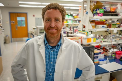 Photo of Charles Danko wearing a lab coat in his lab at the Baker Institute. 