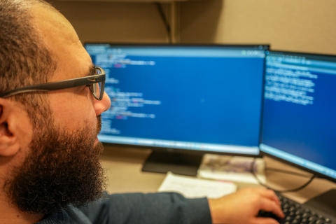 Dr. Shebl Salem sits at his desk while looking at research on the computer. 