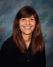 Julia Felippe in a blueish background wearing a black cardigan.