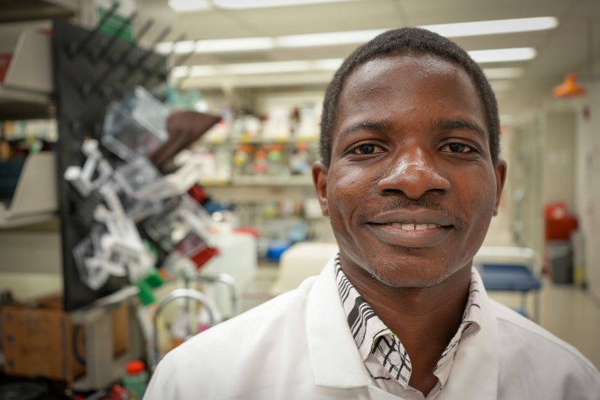 A student wearing a white lab coat stands in a lab at CVM.