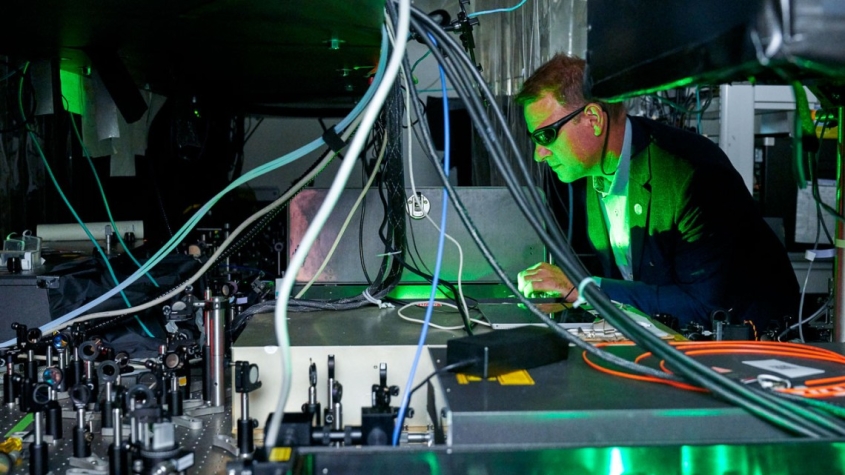 scientist in engineering lab with green lasers