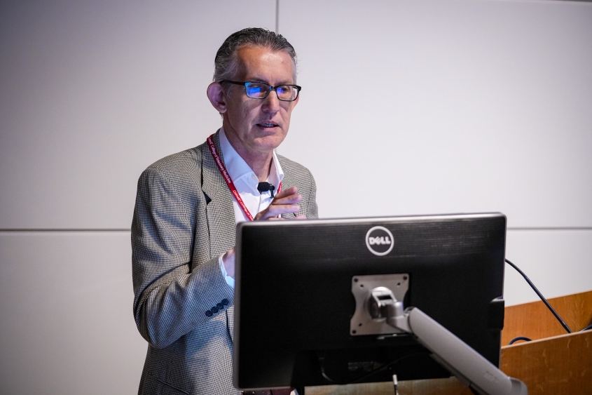 A man with short hair and glasses stands at a podium during a lecture at CVM.