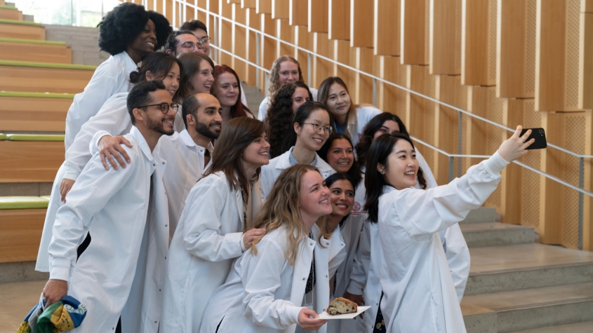 A group selfie of students in white lab coats