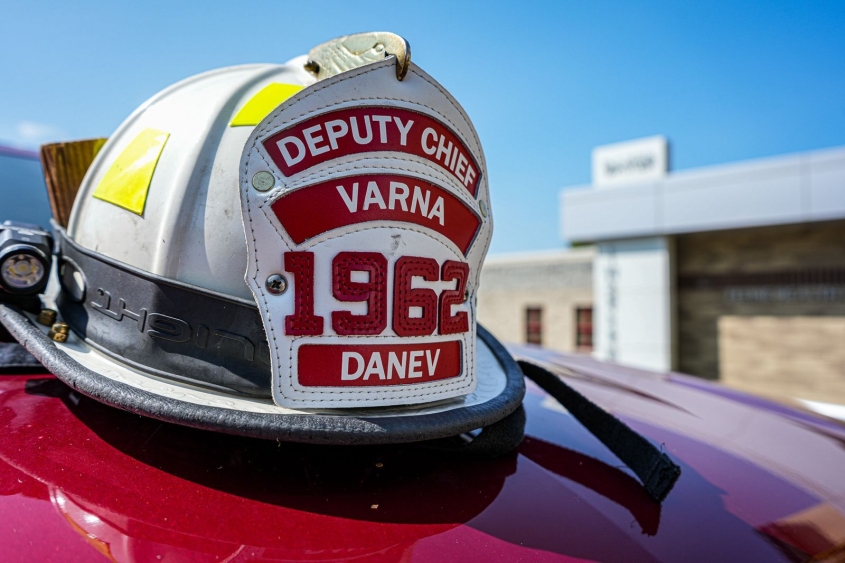 A Varna firefighter helmet sits on the hood of a red vehicle. 