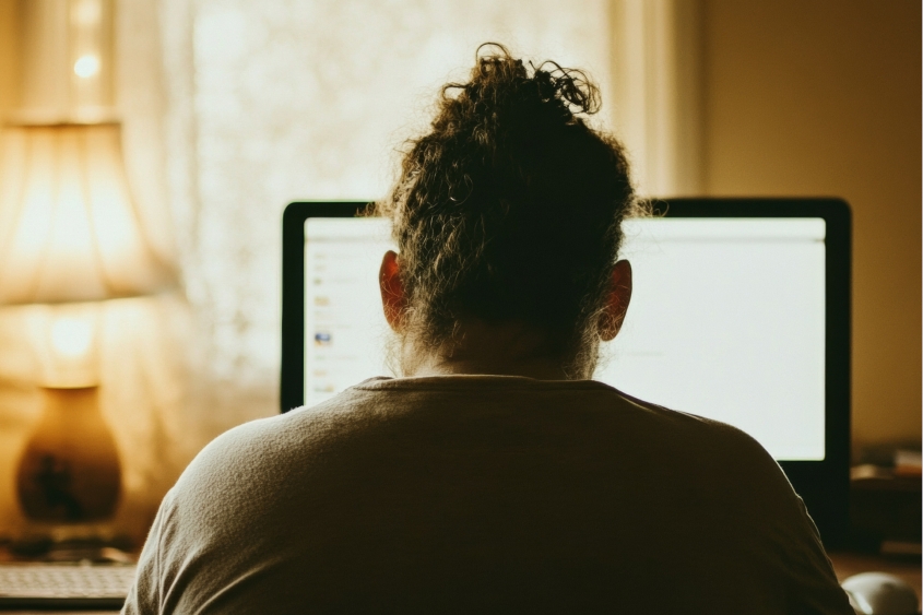 A person seen from the back, looking at a computer screen