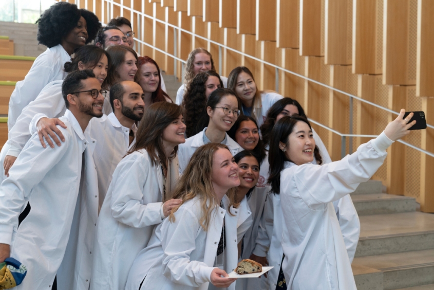 Students in white coats taking a group selfie