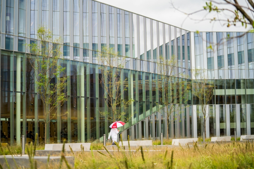 A rainy Lefty's Plaza with a clinician walking across the courtyard holding a Cornell umbrella
