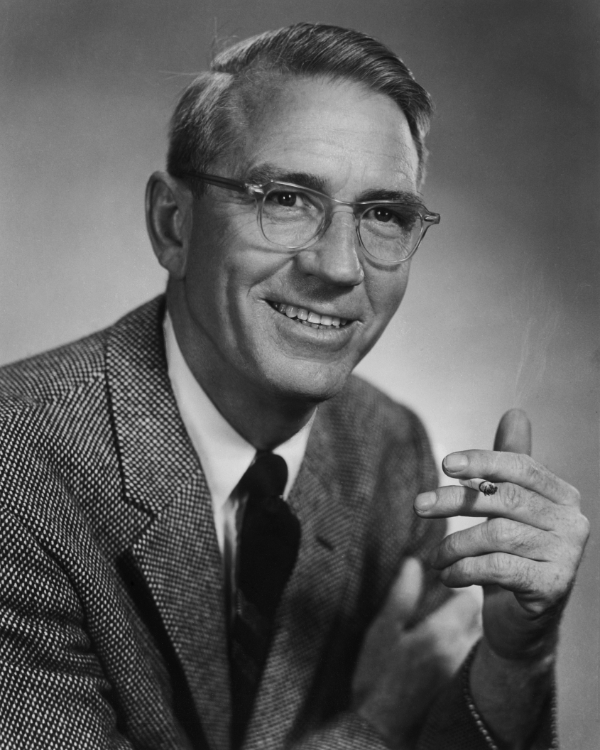 Headshot showing a man with glasses in a suit. 