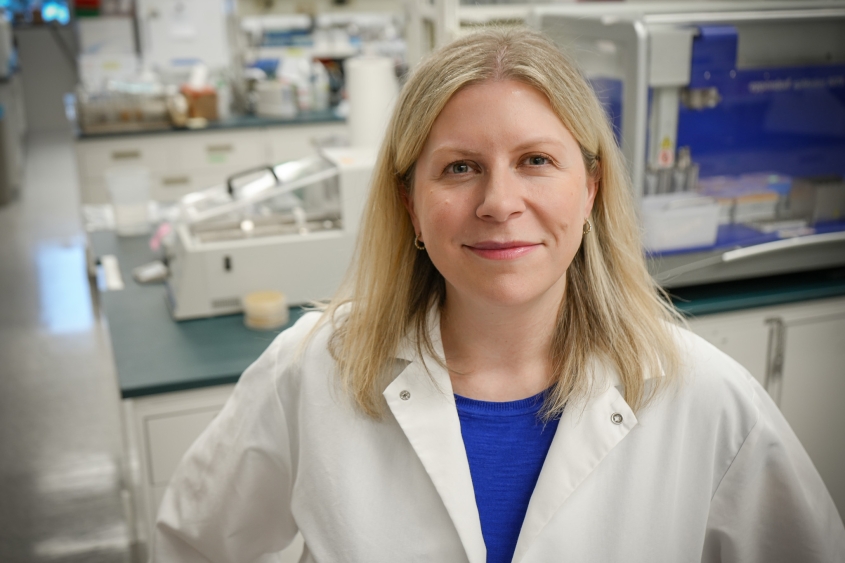 A woman with light hair stands in her lab at the Baker Institute. 