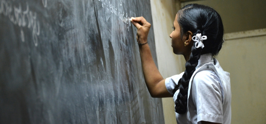 A school girl writing on a black board 