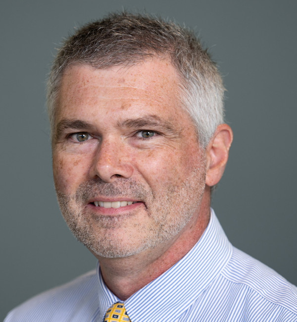 Kevin Cummings wearing a white collared shirt with light blue lines.