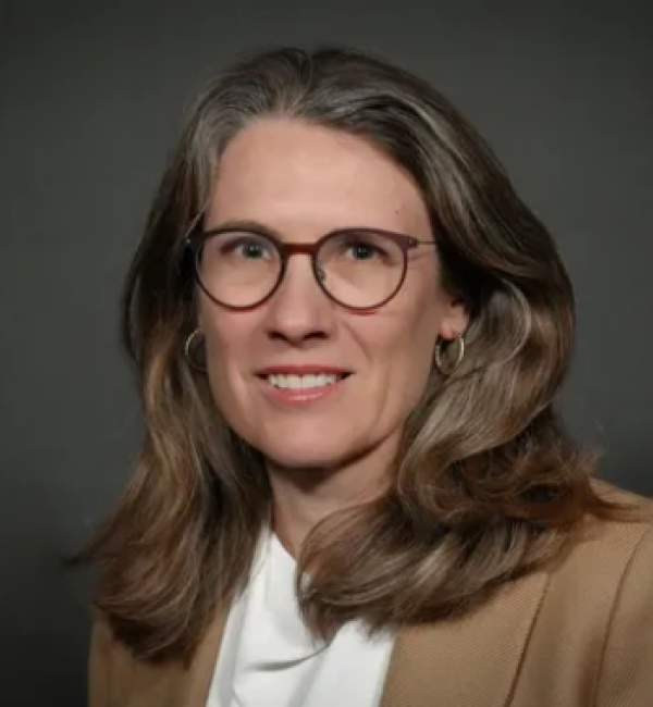 Portrait photograph of Dr. Mandi de Mestre smiling at the camera in front of a dark background