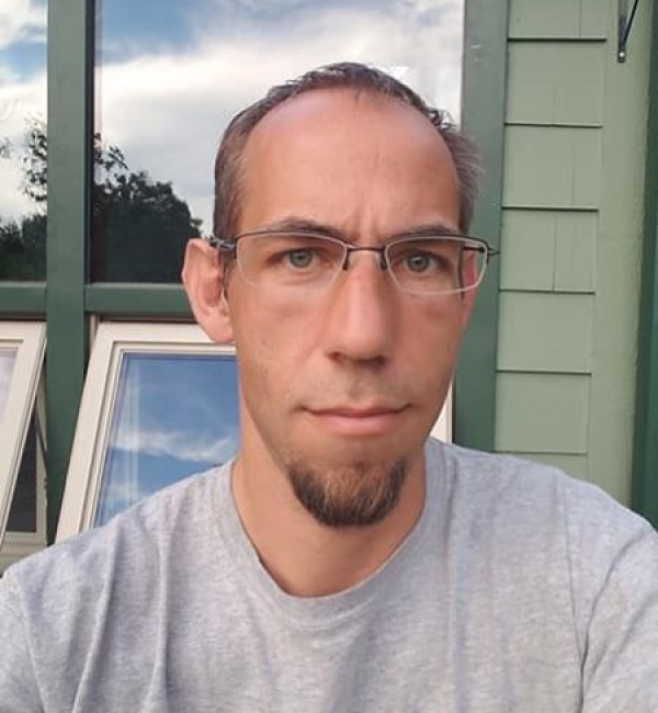 Brian Lazzaro wearing a grey shirt outside.